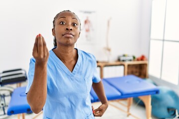 Black woman with braids working at pain recovery clinic doing italian gesture with hand and fingers confident expression