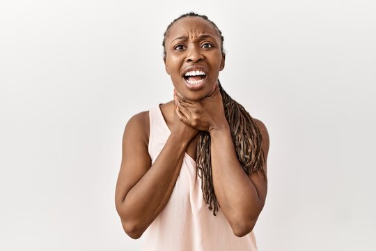 Black woman with braids standing over isolated background shouting and suffocate because painful strangle. health problem. asphyxiate and suicide concept.