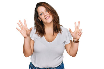 Young plus size woman wearing casual white t shirt showing and pointing up with fingers number eight while smiling confident and happy.