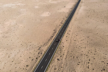Aerial view of a straight road crossing a desert valley near Caleta de Famara in Lanzarote, Canary Islands, Spain.