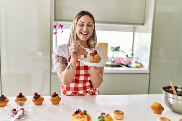 Young caucasian girl smiling happy cooking pumpkins at the kitchen.