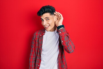 Young hispanic man wearing casual clothes smiling with hand over ear listening an hearing to rumor or gossip. deafness concept.