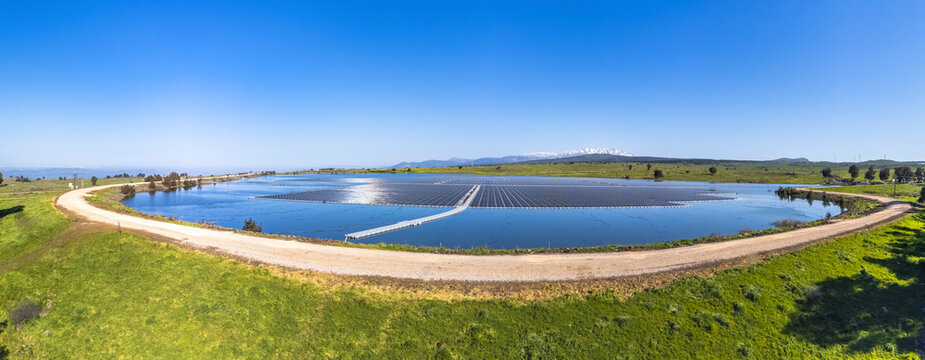 Panoramic aerial view of a water reservoir covered with floating solar panels, Orvim Reservoir, Golan Heights, Israel.