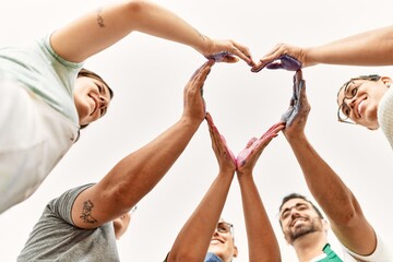 Group of people doing heart sign with hands together at art studio.