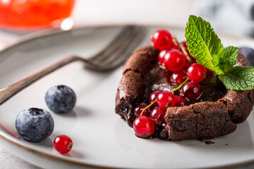 Hot chocolate pudding lava cake with fondant centre, red currants, bleuberry and mint leaves on...