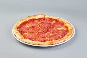 Pepperoni pizza on white plate on gray background
