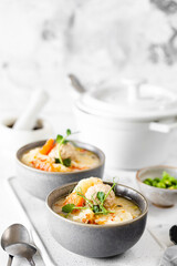 Soup with chicken meatballs and spring vegetables on a white background. Vertical.