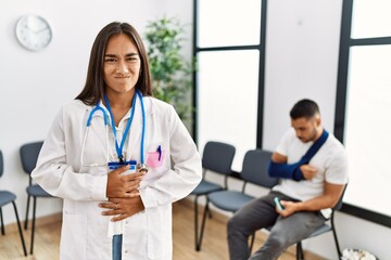 Young asian doctor woman at waiting room with a man with a broken arm with hand on stomach because nausea, painful disease feeling unwell. ache concept.