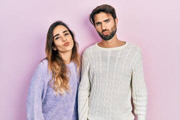 Young hispanic couple wearing casual clothes looking at the camera blowing a kiss on air being...