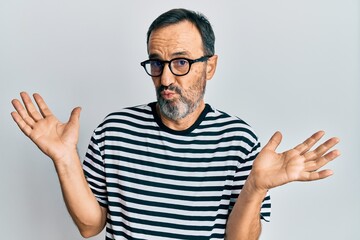 Middle age hispanic man wearing casual clothes and glasses clueless and confused with open arms, no idea and doubtful face.