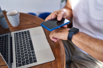 Middle age man using smartphone and watch at terrace home