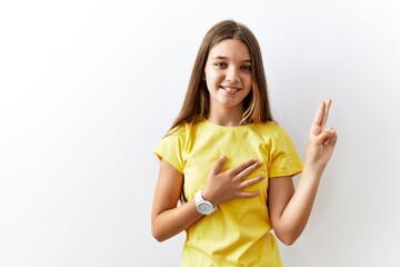 Young brunette teenager standing together over isolated background smiling swearing with hand on...