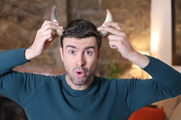 Sad man holding pair of horns - obrazy, fototapety, plakaty