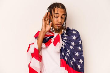 Young African American man holding a American flag isolated on white background trying to listening a gossip.