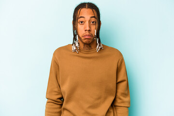 Young African American man isolated on blue background shrugs shoulders and open eyes confused.