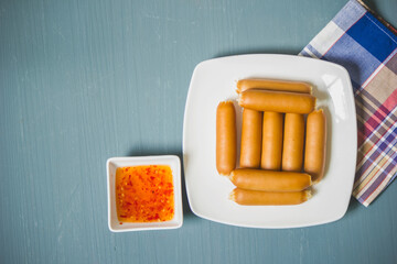 Smoked Chicken Sausage cooked with dipping sauce on a plate and placed on the table.