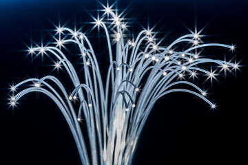 Bundle of optical fibers with lights in the ends. Dark blue background.