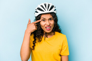 Young hispanic woman wearing a helmet bike isolated on blue background showing a disappointment gesture with forefinger.