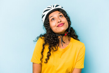 Young hispanic woman wearing a helmet bike isolated on blue background dreaming of achieving goals and purposes