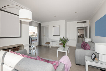 Living room of a vacation rental apartment with access to a terrace and with gray sofas and white wooden furniture