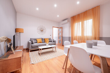 Living room with white dining table, wooden furniture, three-seater sofa and tv on sideboard