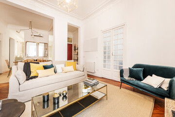 Living room with a large three-seater sofa and a two-seater blue velvet sofa, a metal coffee table and mirrors and wood carpentry on the doors