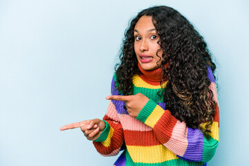 Young hispanic woman isolated on blue background shocked pointing with index fingers to a copy space.