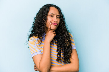Young hispanic woman isolated on blue background unhappy looking in camera with sarcastic expression.
