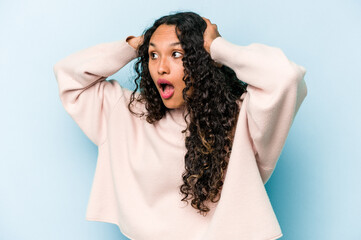 Young hispanic woman isolated on blue background screaming, very excited, passionate, satisfied with something.