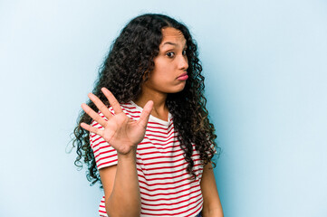 Young hispanic woman isolated on blue background rejecting someone showing a gesture of disgust.