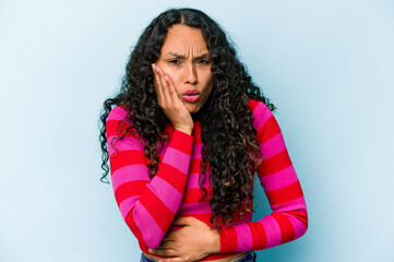 Young hispanic woman isolated on blue background blows cheeks, has tired expression. Facial expression concept.