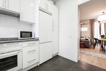 White kitchen with matching appliances, gray granite countertop, white microwave and walkout to living room and dining room
