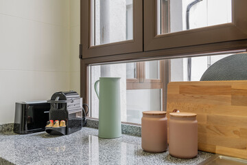 Corner of a kitchen with small appliances on the gray granite countertop