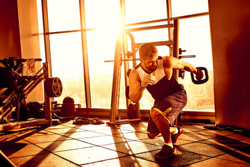 Portrait of a handsome man doing push ups exercise with modern weight equipment in rays of sunlight...