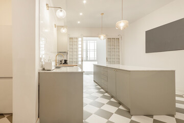 Fototapeta na wymiar Large kitchen with appliances with smooth gray furniture and white appliances, white stone countertop and island of the same material, glass doors with white wood