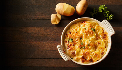Top view of appetizing gratin baked potato with cheese and chopped parsley