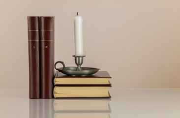 Candle holder and old style books against white background