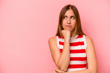 Young caucasian woman isolated on pink background looking sideways with doubtful and skeptical expression.