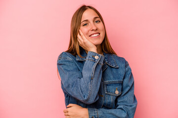 Young caucasian woman isolated on pink background laughs happily and has fun keeping hands on...