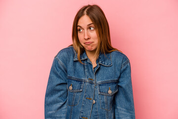 Young caucasian woman isolated on pink background shrugs shoulders and open eyes confused.