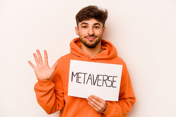 Young hispanic man holding a metaverse placard isolated on white background smiling cheerful...