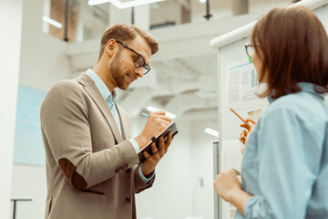 Obraz premium Man in eyeglasses writing notes in his notebook