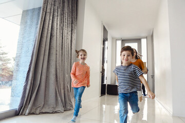 Happy family running in hall. Funny kids jumping with carton box, parents laughing,
