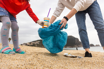 Asian woman picking bottle into plastic bag black for cleaning the beach in morning time, Volunteer concept