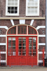 Amsterdam Street View with Old Brick Building Facade, Red Entrance and Iron Fence Close Up, Netherlands