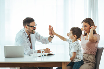Side view smiling friendly male pediatrician in glasses and white medical coat giving high five to...
