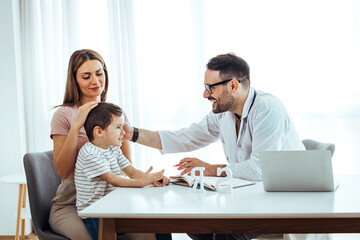 Mother and son at the doctor's office. Friendly male practitioner talking to child during health...