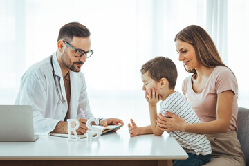 Concept of trustworthy method of consultation in healthcare system. Waist up portrait of smiling little boy with pediatrician man in medical cabinet. Mother and her son consulting with doctor
