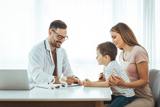 Close up of a young family at a Pediatrician's Office. Smiling male pediatrician listening to young mother with kid son. professional children doctor consultation, healthcare concept.