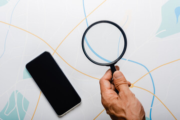 Spy agent with smartphone and magnifying glass looking at city map